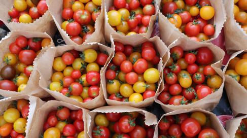 Small red and yellow tomatoes divided into paper bags