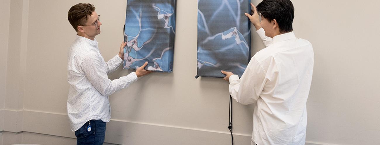 Cluster Research Coordinator Jake Winkler (left) and graduate student Xudong Wang hang the ART devices in a classroom on UBC Okanagan’s campus. This room will be the site of the Campus as a Living Lab project looking into the effectiveness of the filter device. ART-device